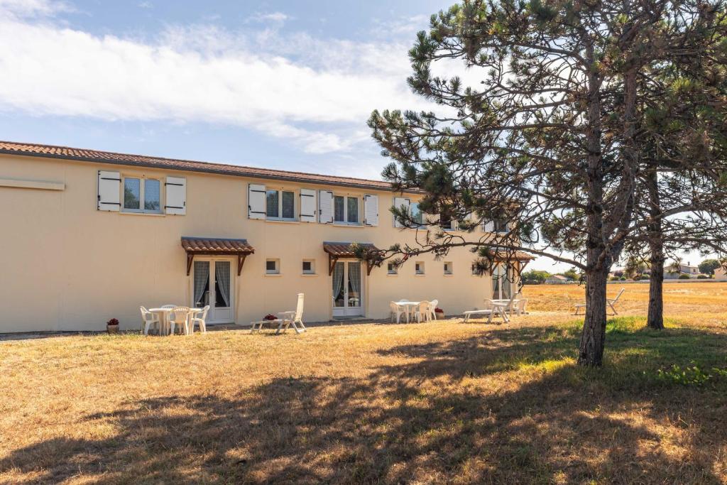 an external view of a house with tables and a tree at Duplex N°2 - Résidence Balnéaire in Le Port-des-Barques