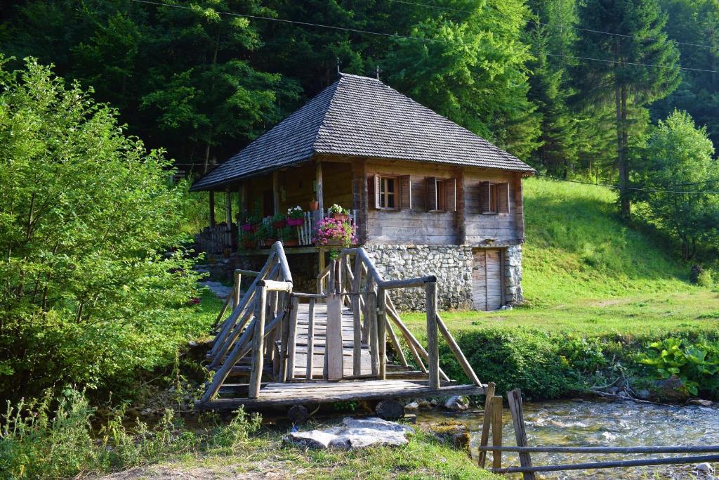 a small house on a hill next to a river at Autocamp & Apartment Snežana in Berane