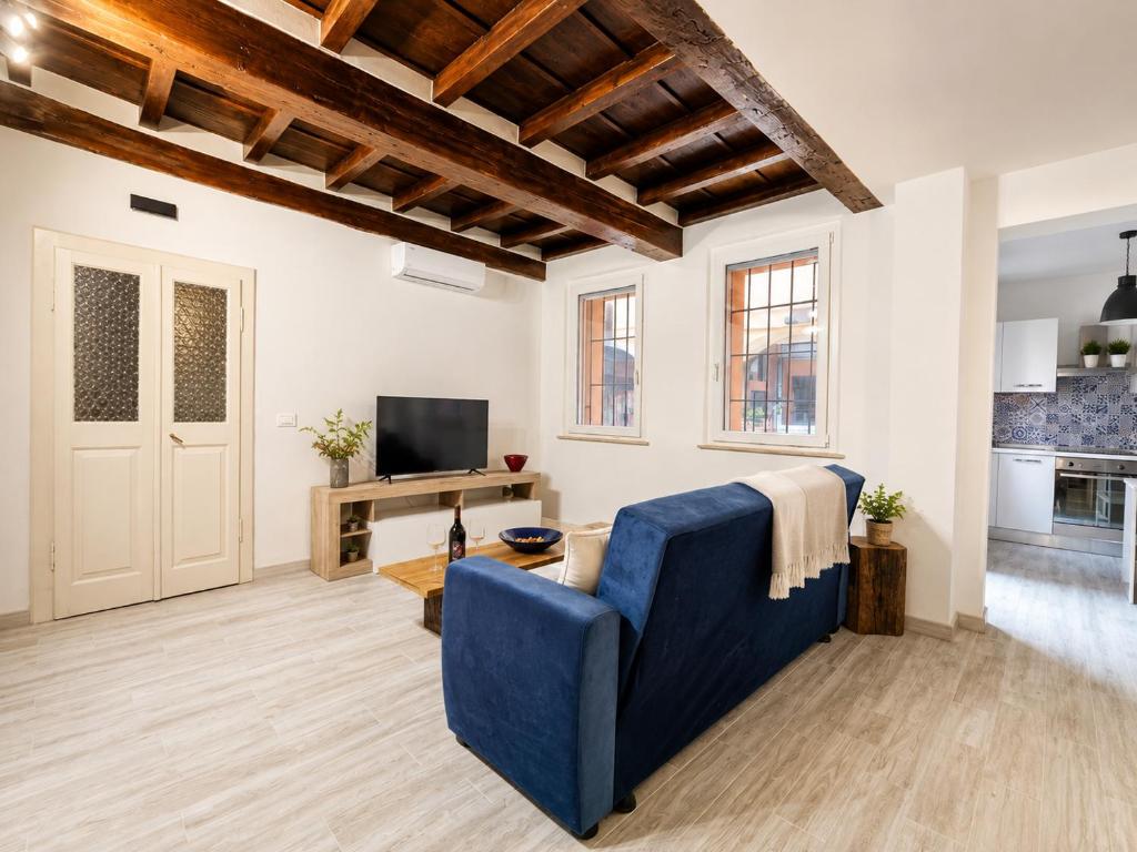 a living room with a blue couch and a tv at Il Rifugio di Trip Centro Storico & Lago in Mantova