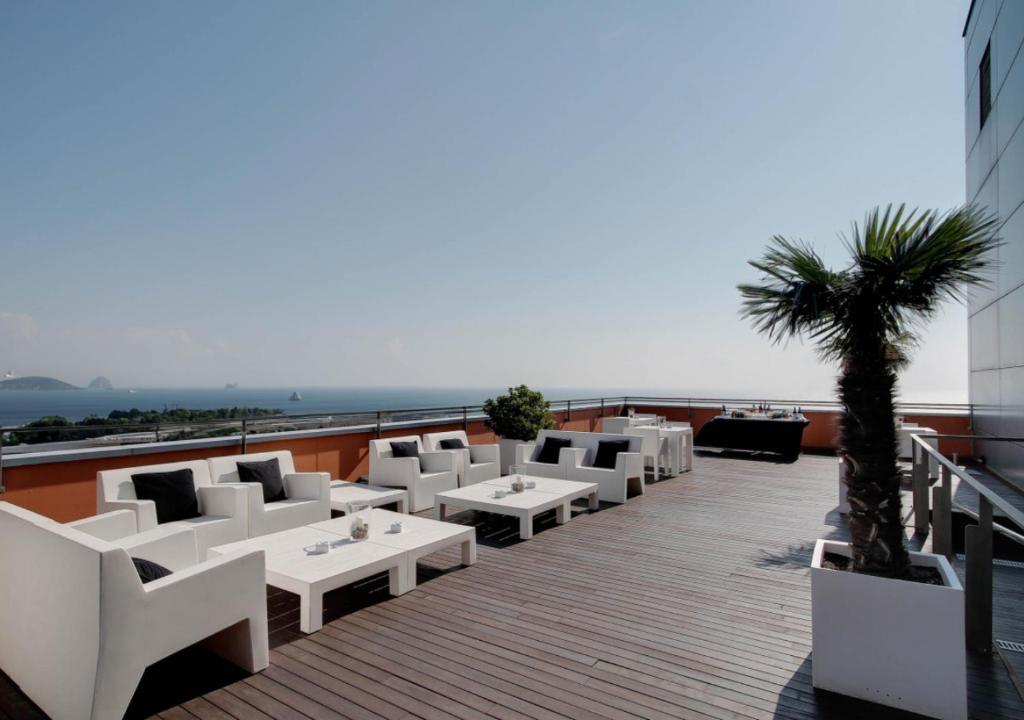 a balcony with white chairs and tables on a building at Hotel Badalona Tower in Badalona