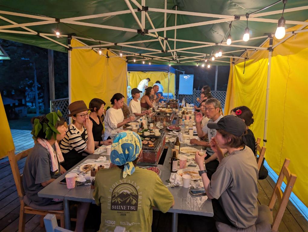 a group of people sitting at a long table eating at Myoko Mountain Lodge in Myoko