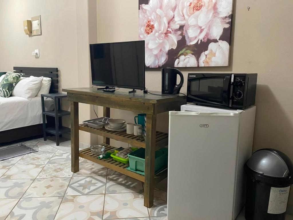 a room with a desk with a television and a microwave at Meerensee tranquil suite in Richards Bay