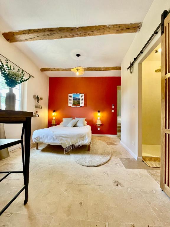 a bedroom with a bed and a red wall at Mas du Rocan in Aubignan