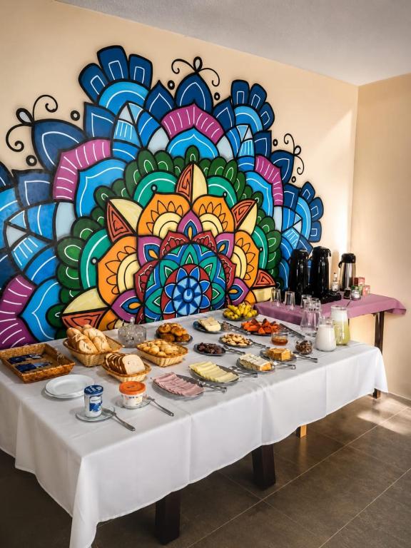 a table with food on it in front of a colorful wall at Pousada Quintal da Cachoeira in São Thomé das Letras