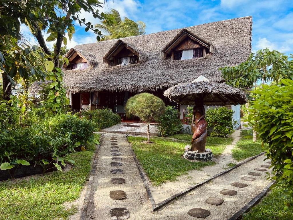 a house with a grass roof with a statue in front of it at Mahanoro Hotel & Restaurant in Sainte Marie