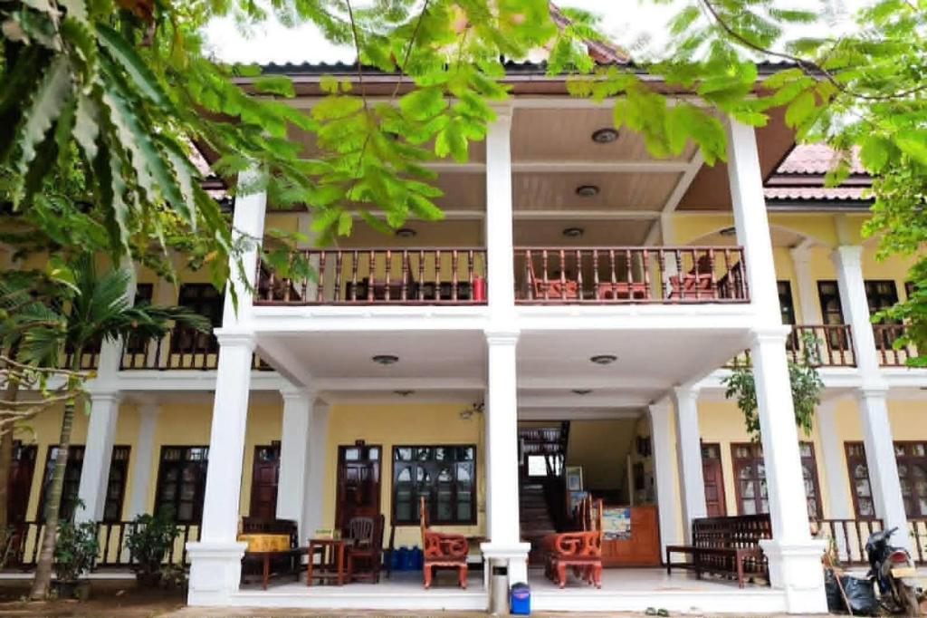 a large white building with tables and chairs at Dokban Hotel in Luang Prabang