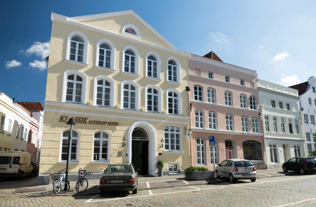 een groot gebouw met auto's geparkeerd voor het bij TOP CityLine Klassik Altstadt Hotel Lübeck in Lübeck