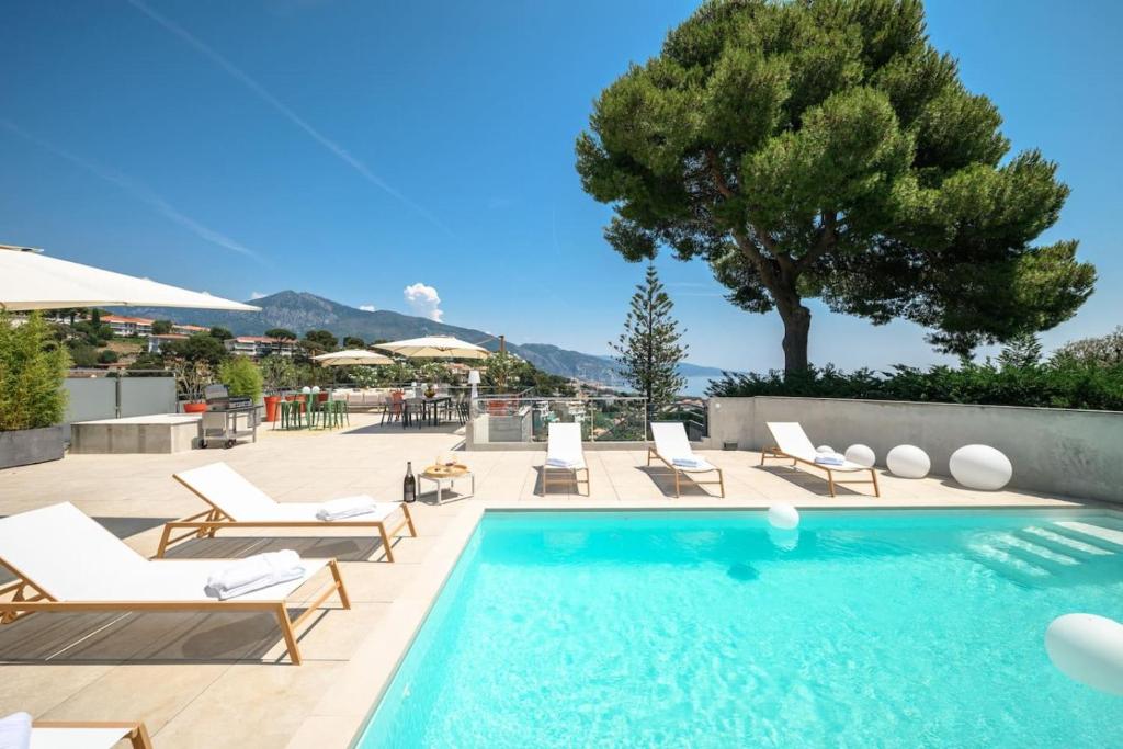 a swimming pool with lounge chairs and a tree at Villa Romy, a World apart in Roquebrune-Cap-Martin