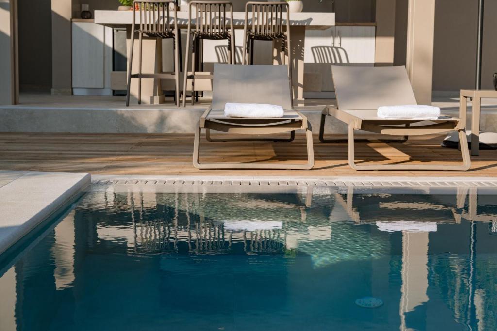 two chairs sitting next to a swimming pool at Villa Idola Dassia Corfu in Dassia