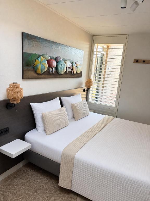 a bedroom with a large white bed and a window at Bed & Beach Zeekraal in De Koog