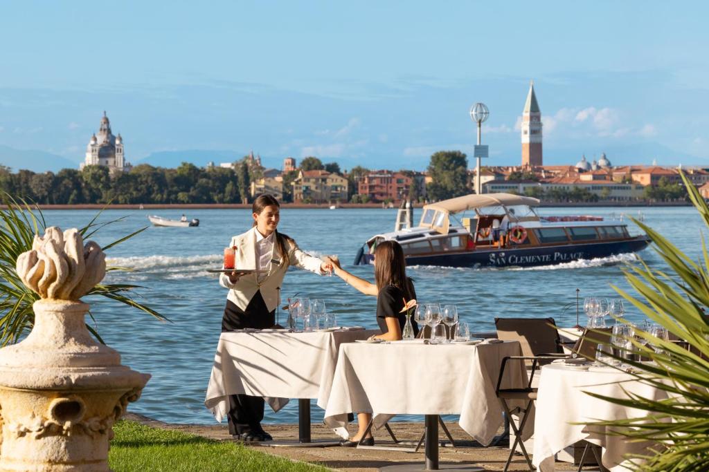 a man and woman sitting at a table near the water at San Clemente Palace Venice in Venice