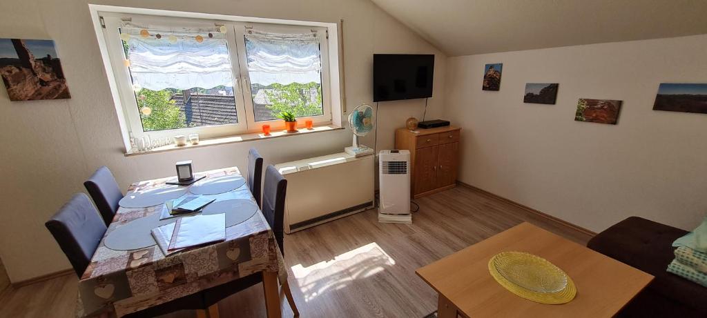 a living room with a dining room table and a window at Höllenbergblick in Spirkelbach