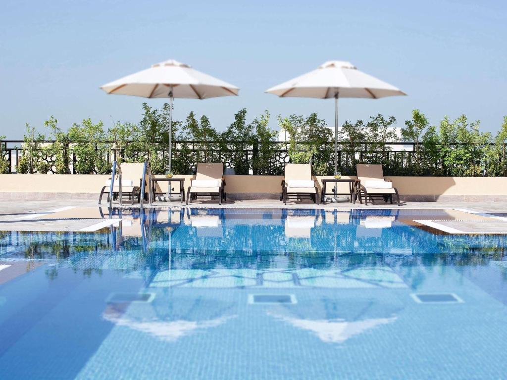 a swimming pool with chairs and umbrellas at Mövenpick Hotel Apartments Al Mamzar Dubai in Dubai