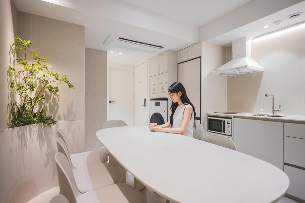 a woman sitting at a white table in a kitchen at 더하다 in Busan
