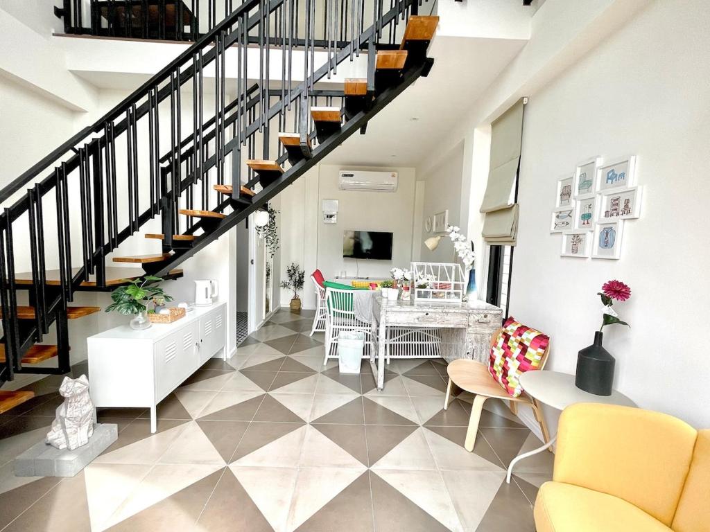 a living room with a staircase and a table and chairs at Milky house in Ban Bang Phai