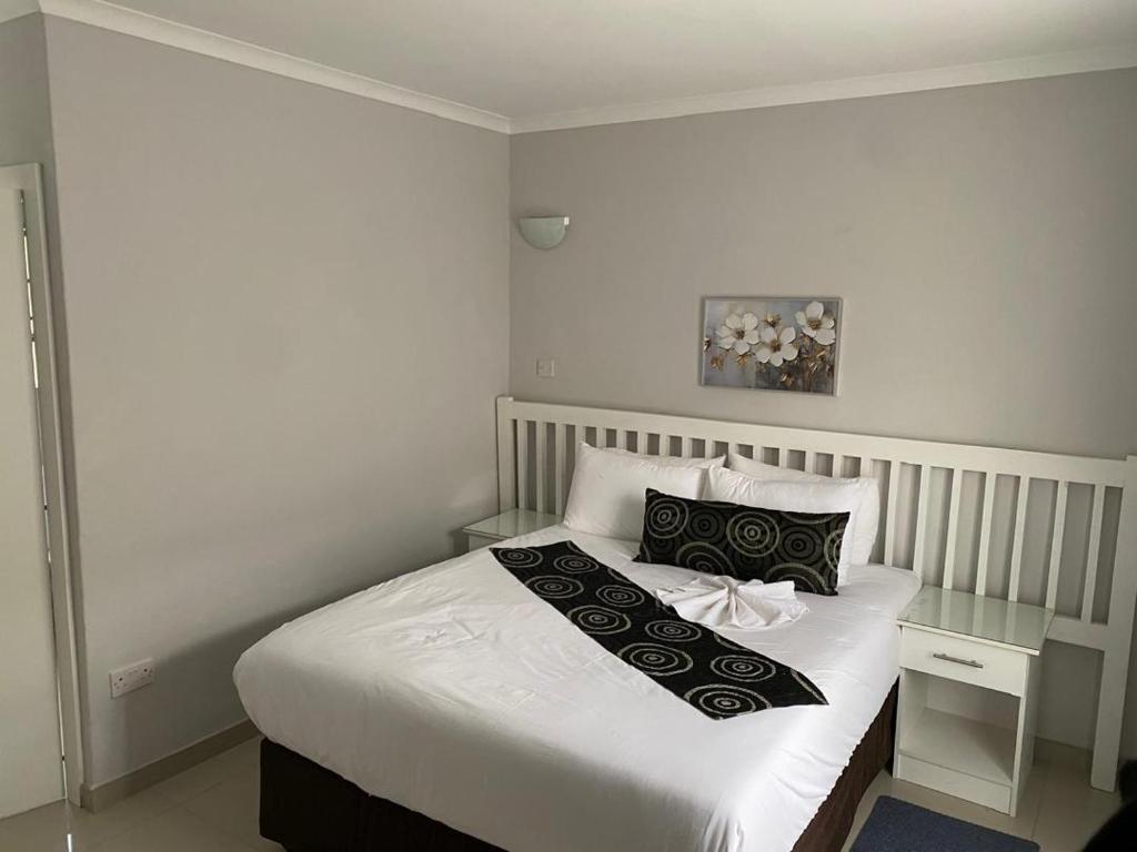ein Schlafzimmer mit einem Bett mit einer schwarz-weißen Decke in der Unterkunft The GL in Gaborone