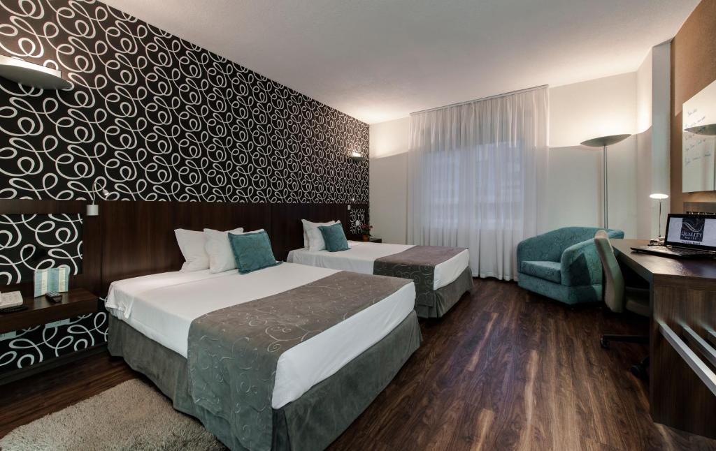 a hotel room with two beds and a desk at Quality Hotel Curitiba in Curitiba