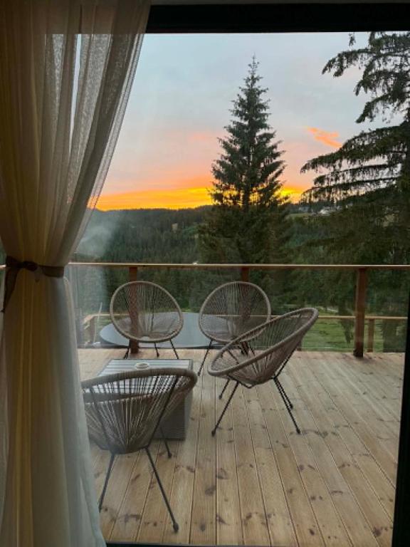 a deck with three chairs and a view of a sunset at SevenHeaven in Mărişel