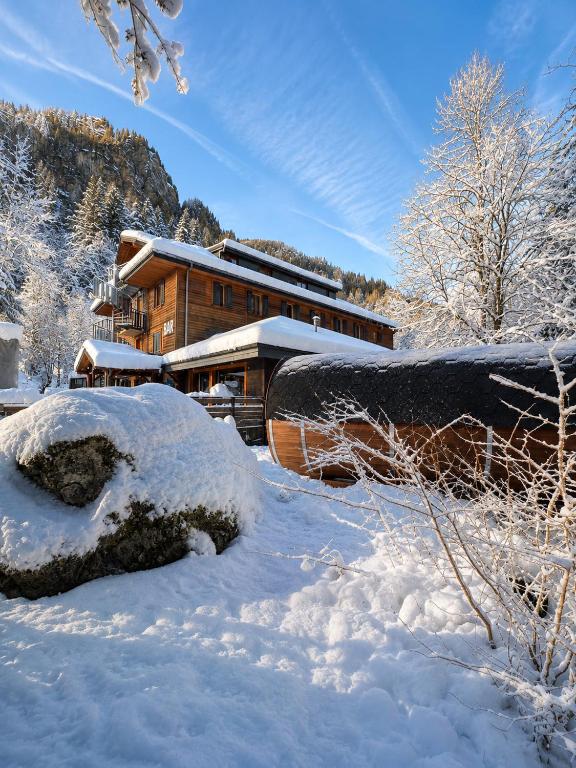 a house covered in snow in front of a building at 1861 Châtel Hostel in Châtel