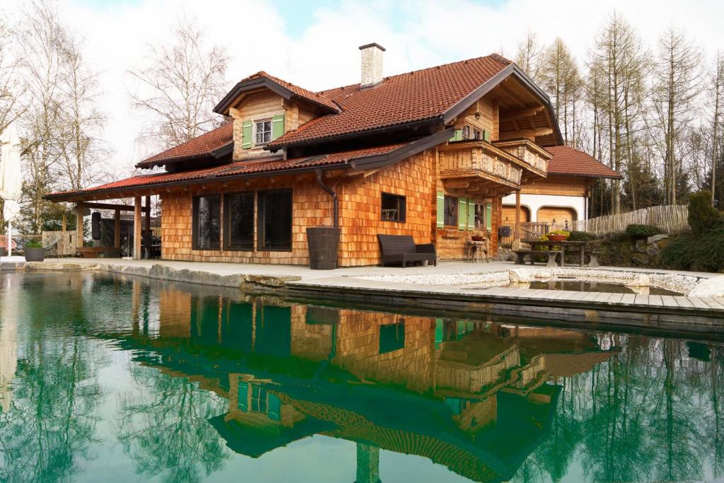 a log house with a pond in front of it at Luxury Chalet with Swimming Pond Nature Escape Upper Austria in Sankt Johann am Walde