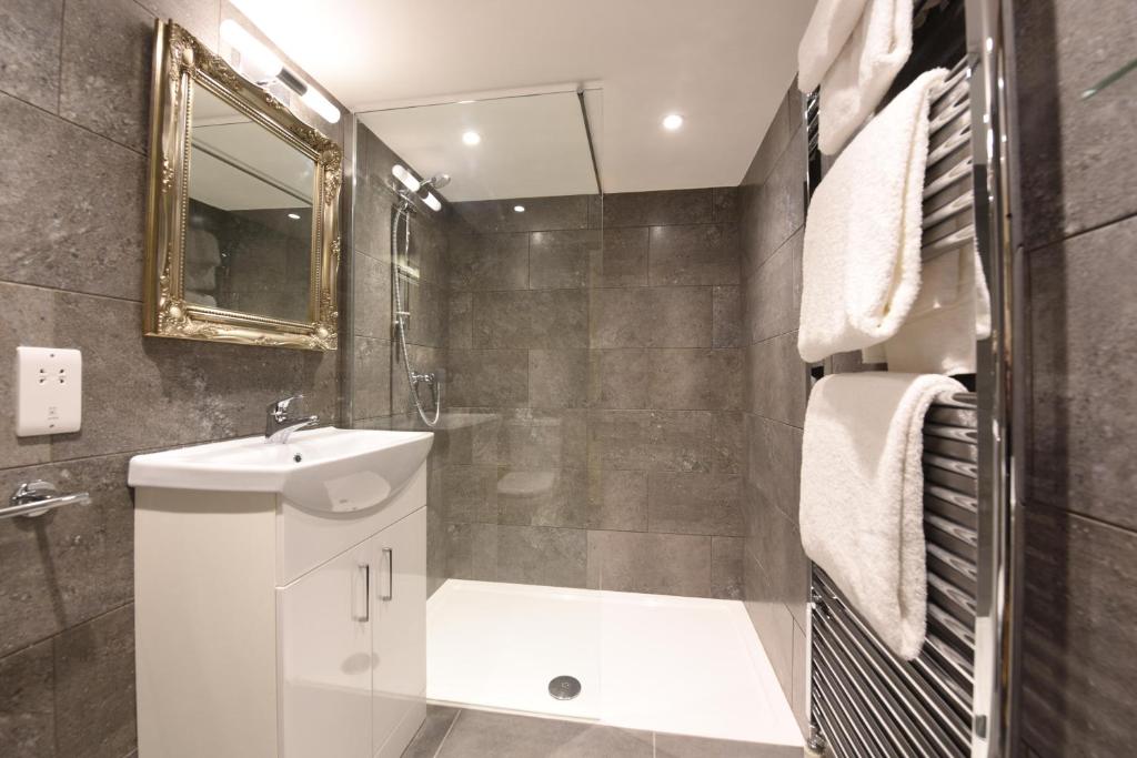 a bathroom with a sink and a toilet and a mirror at Sutherland House in Southwold