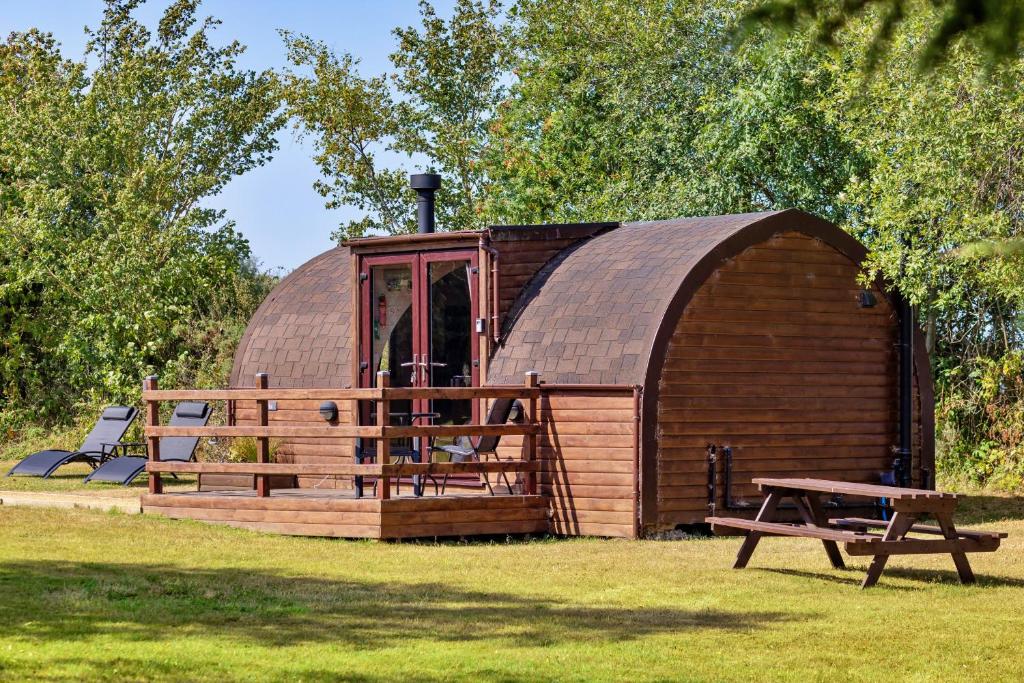 a large wooden cabin with a table and a bench at Finest Retreats - Idris Pod in St Asaph