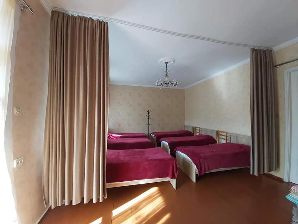 a bedroom with three beds with red sheets at Maias guest house in Kazbegi