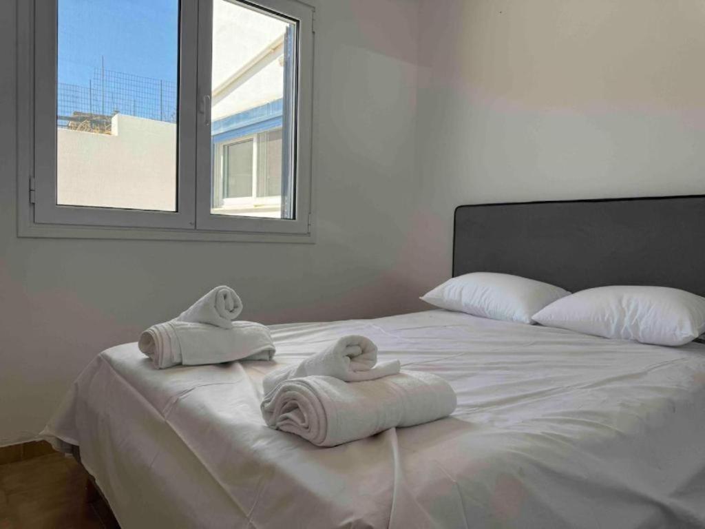 a white bed with towels on it with a window at Kalloni Village House in Kalloní