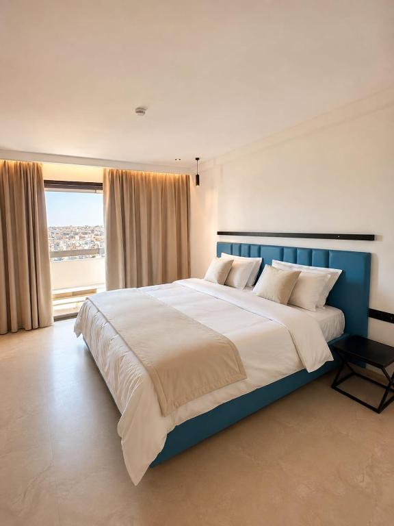 a large bed in a bedroom with a large window at HOTEL KAISER in Sousse