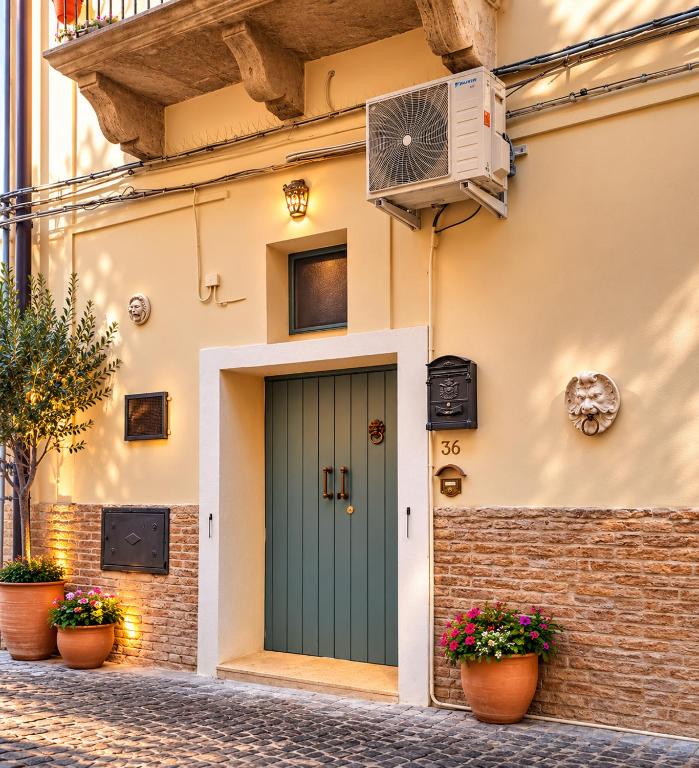 a house with a green door and flower pots at Dimora dei Ciri in Ferrandina