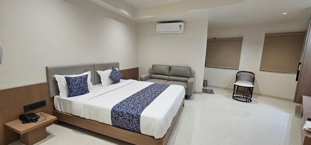 a bedroom with a bed and a chair in it at Hotel Centrum in Surendranagar