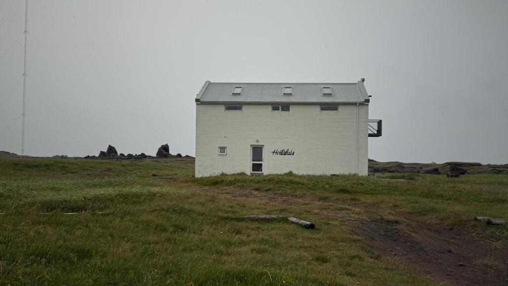 a white building in the middle of a field at Snaefell Apartments in Hellissandur