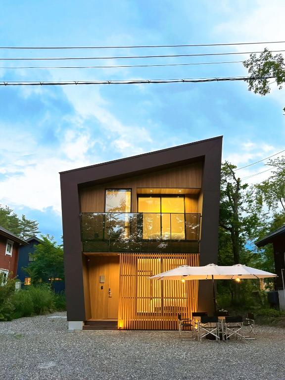 a house with a balcony and a table and an umbrella at KOMU Hakuba in Hakuba
