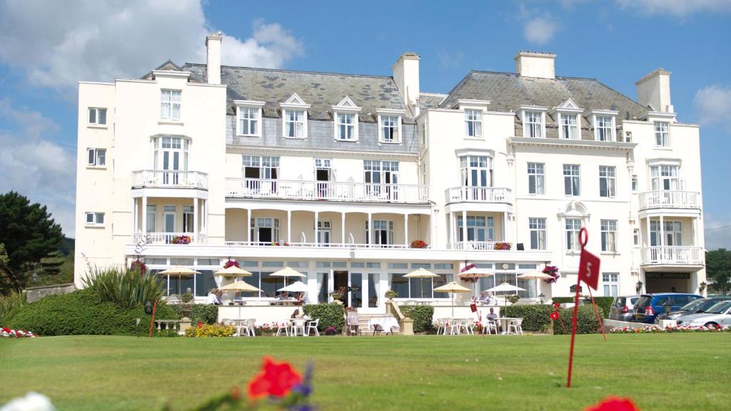 un grande edificio bianco con un prato di fronte di The Belmont Hotel a Sidmouth