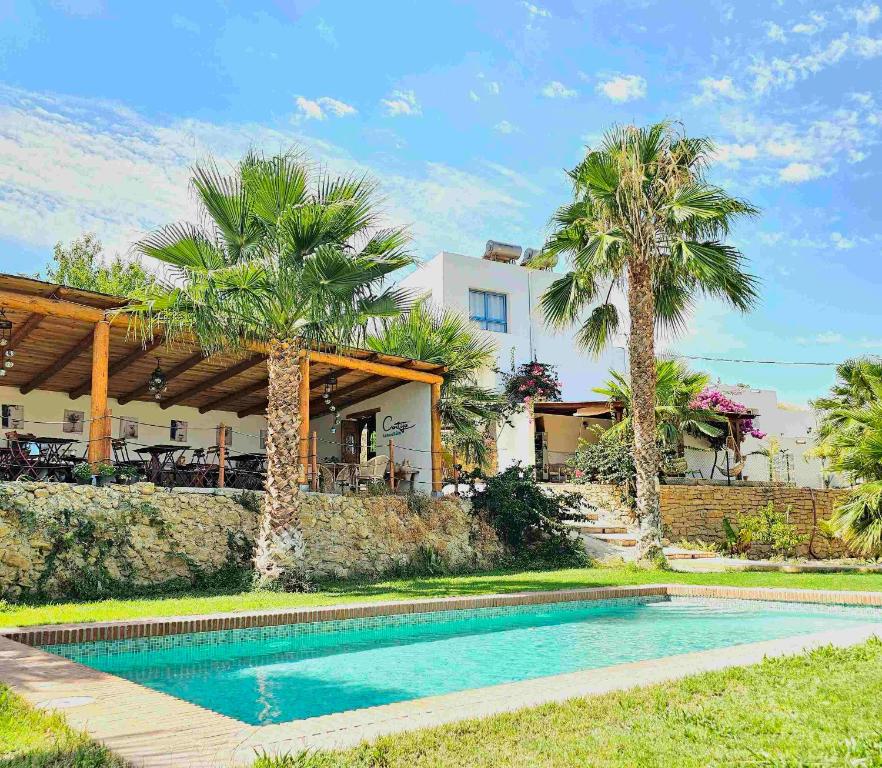 a swimming pool in front of a house with palm trees at B&B La Nava Suites in Mojácar