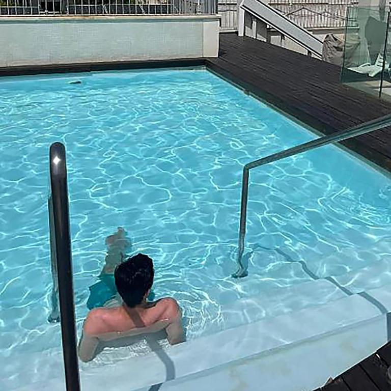 a man sitting in a swimming pool at BONITO APARTAMENTO a 200 metros del centro de Sevilla con piscina y parking gratis in Seville