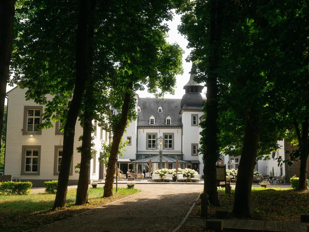 a large white house with a tree lined driveway at Hotel Kasteel Doenrade in Doenrade