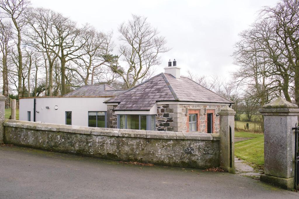 een huis achter een stenen muur met een hek bij Scion Hill Gate Lodge in Hillsborough