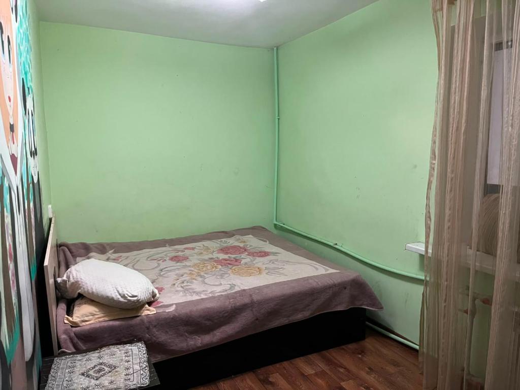 a small bed in a room with green walls at Махамбета in Atyrau