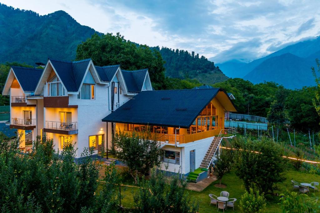 a house with a black roof with mountains in the background at Moustache Pahalgam in Pahalgām