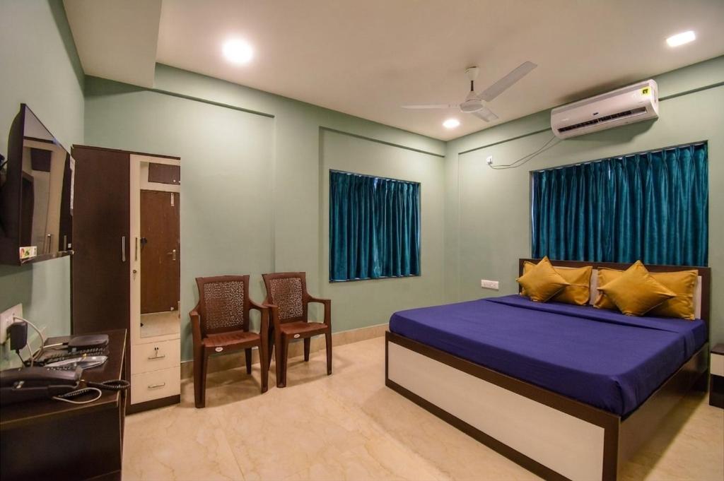 a bedroom with a bed and chairs and a sink at FabHotels Calyra in Karīmnagar