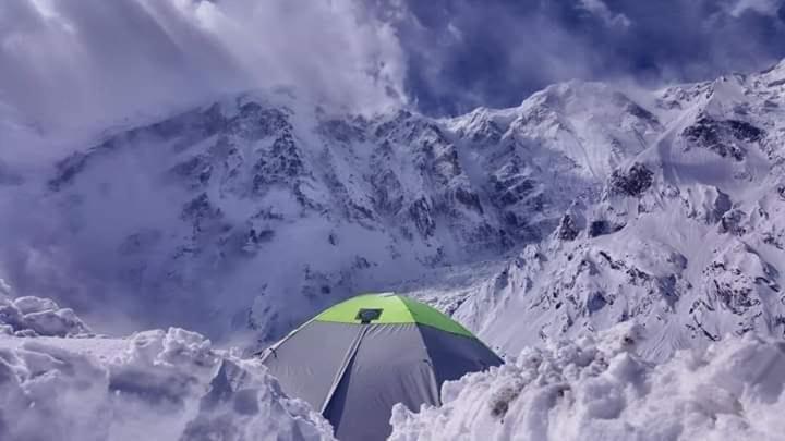 a tent in the snow in front of a mountain at Hello Rakaposhi Camping Site in Gilgit