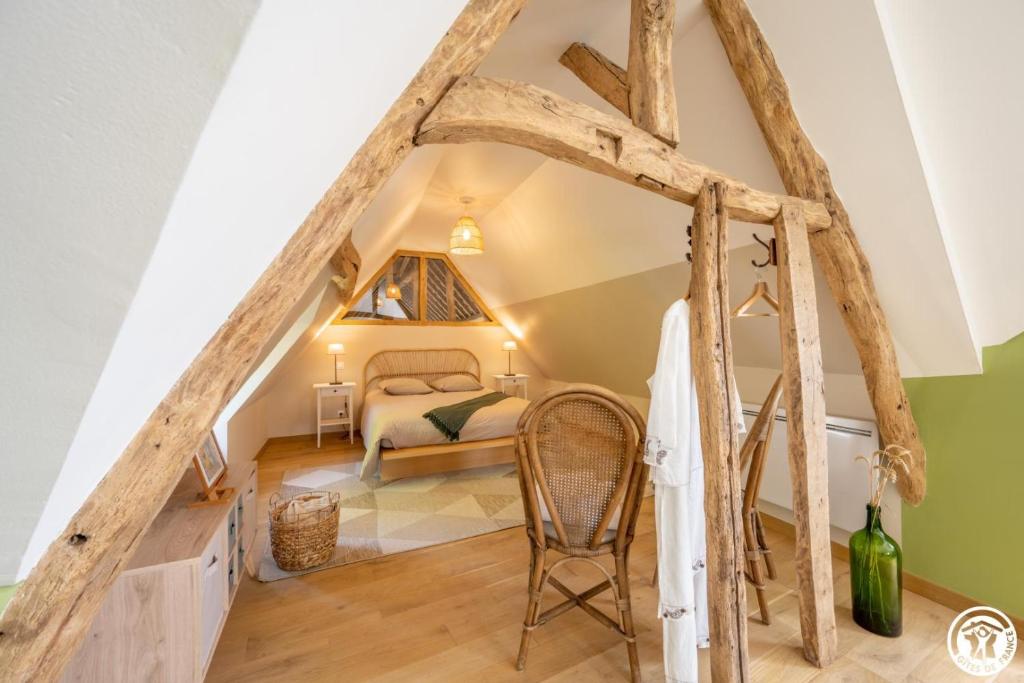a room in the attic with a bed and a chair at Le clos bambou in Loueuse