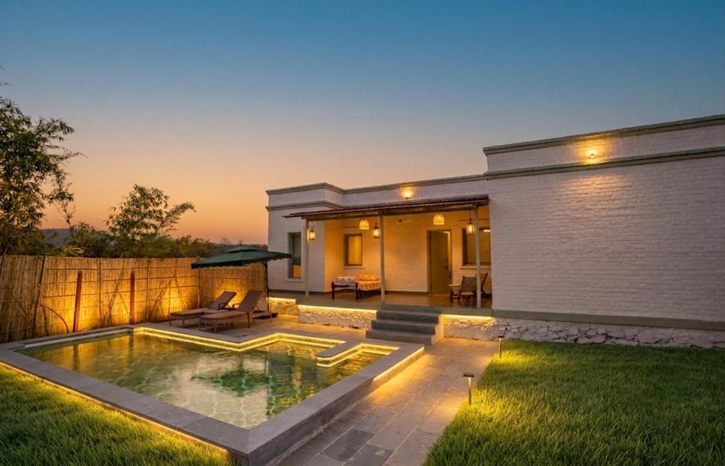 a backyard with a swimming pool and a house at Kadamb Bagh-A Luxury Nature Resort Sariska in Rāmsinghpura