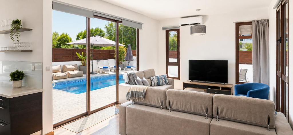 a living room with a couch and a television at Palm Tree Villa By Staycom in Oroklini