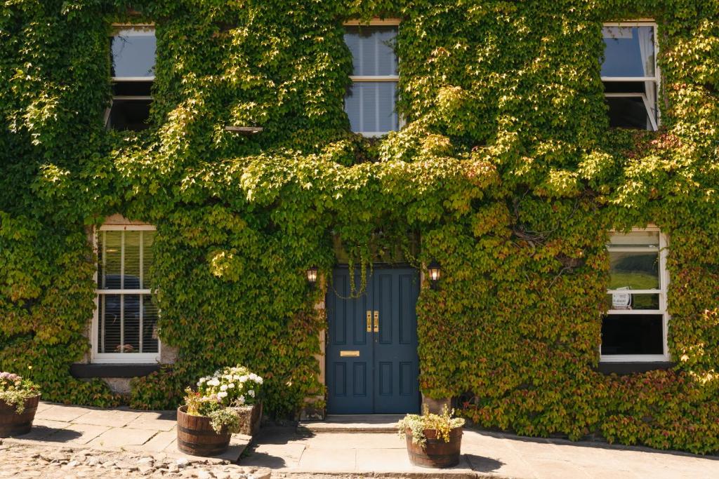 a building covered in green ivy with a blue door at Aysgarth Falls Hotel & Restaurant in Aysgarth
