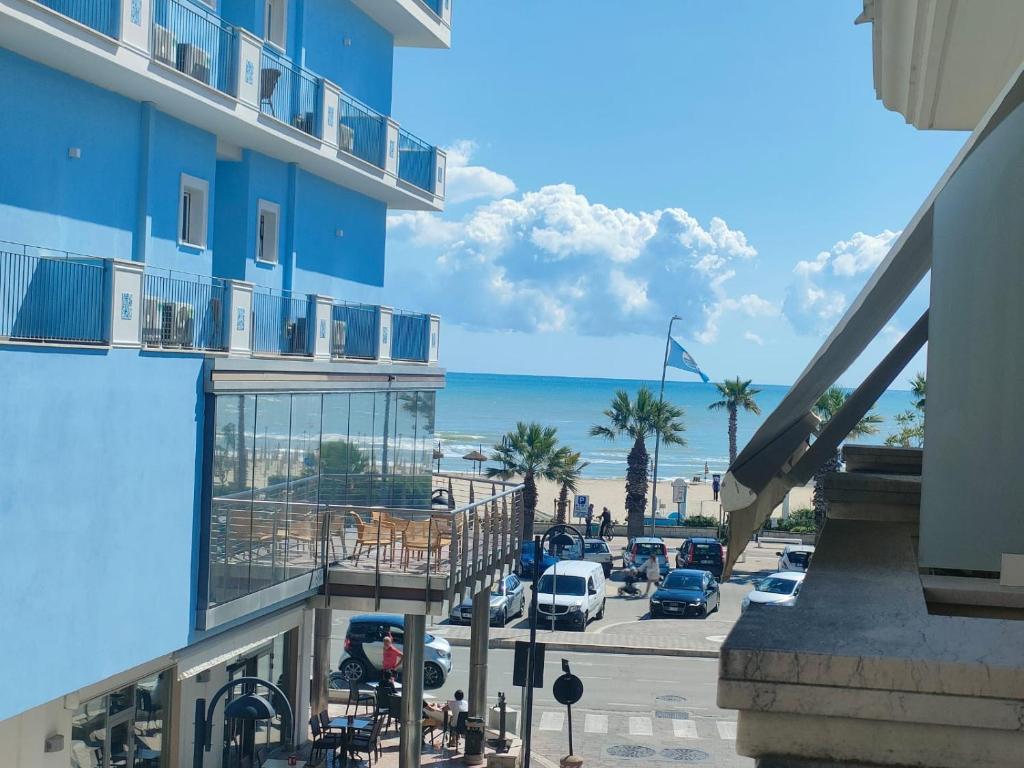 a blue building with a parking lot and the ocean at Carducci Sunrise in Tortoreto Lido