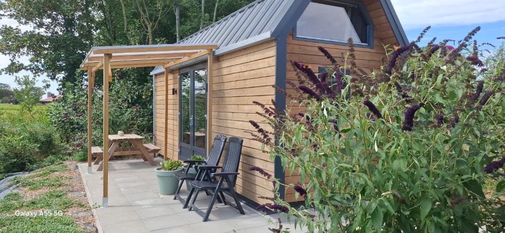 a small cabin with a table and chairs in a garden at Buorkerijhûske A - Tussen Wad en Weide in Hallum