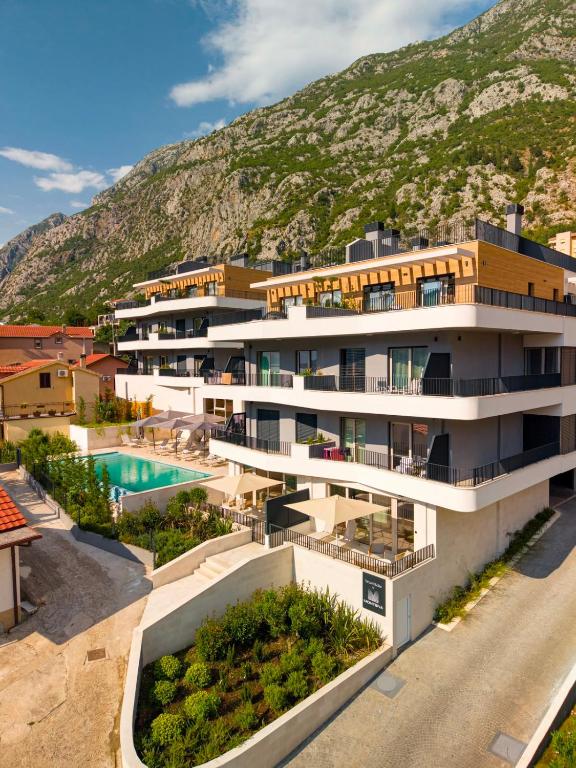 an apartment building with a mountain in the background at Vrtovi Boke by Montena in Dobrota