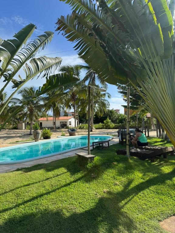 a pool with a palm tree in a yard at Pousada Maraí in Amontada